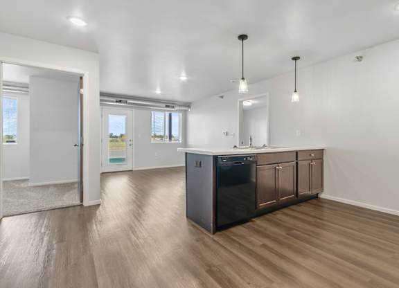 A kitchen with a black dishwasher and wooden floors.