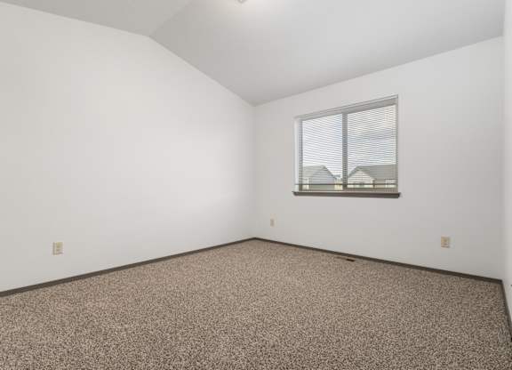 A room with a window and carpeted floor.