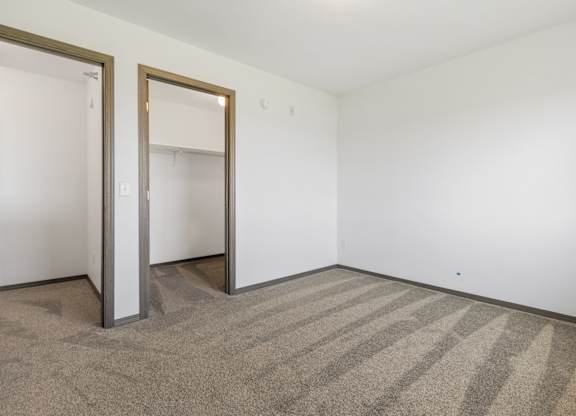 A room with a striped carpet and two open doors.