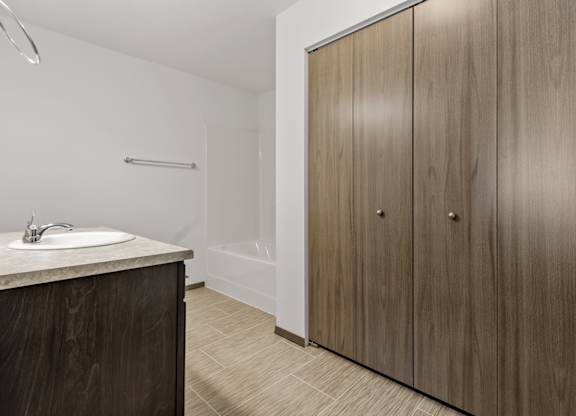 A bathroom with a sink, a shower, and a wooden cabinet.