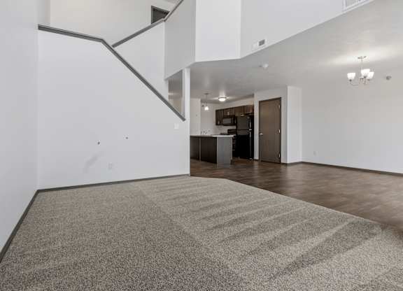 A room with a carpeted floor and a staircase.