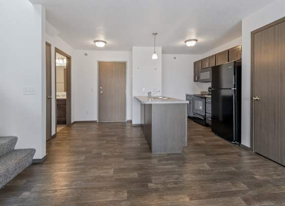 A modern kitchen with a refrigerator, sink, and cabinets.