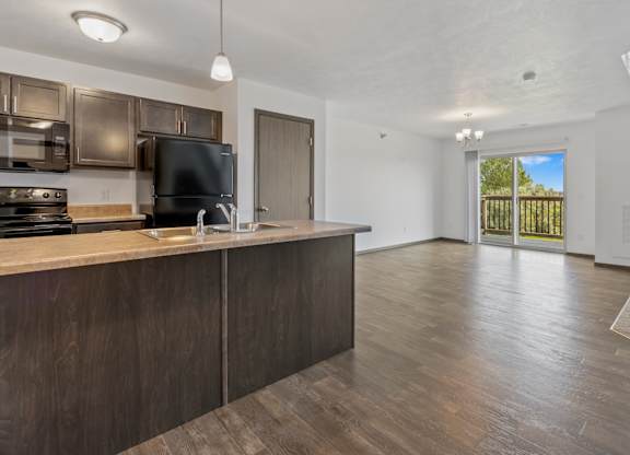 A kitchen with dark wood cabinets and a black fridge.