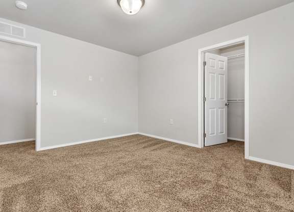 A room with carpeted floor and two doors.