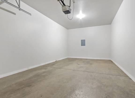 A room with a concrete floor and a white wall with a small square object on it.
