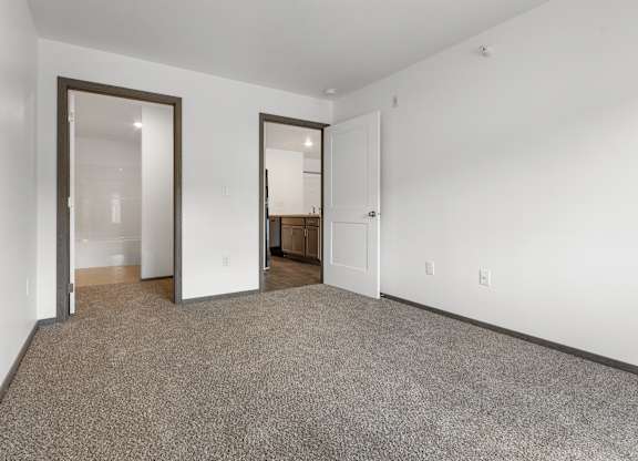 A room with carpeted floor and two open doors.