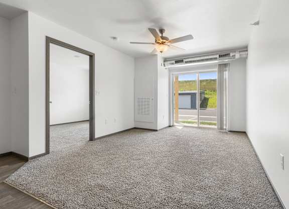 A room with a carpeted floor and a ceiling fan.