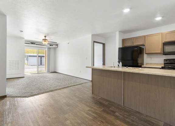 A kitchen area with wooden cabinets and a black microwave.