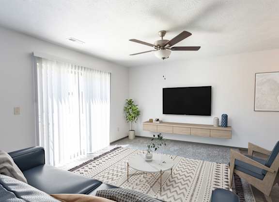 A living room with a blue couch, a white coffee table, and a black television on a wooden stand.