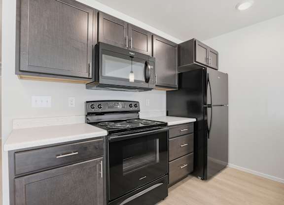 A kitchen with black appliances and wooden cabinets.