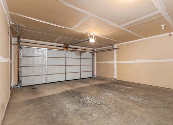A large, empty garage with a concrete floor and white walls.