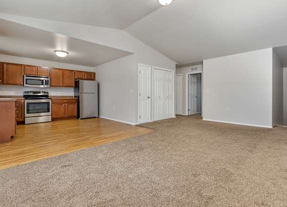 A spacious living room with a kitchen area in the background.
