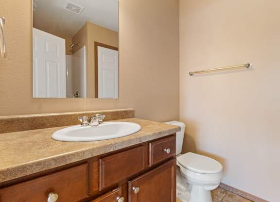 A bathroom with a sink, toilet and mirror.