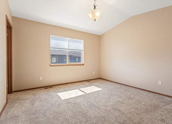 A room with a window and a carpeted floor.