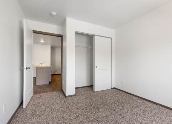 A carpeted room with a white door and a mirror.
