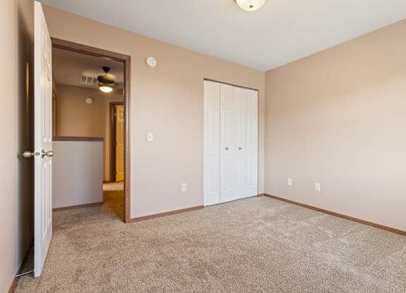 A room with a carpeted floor and two doors.