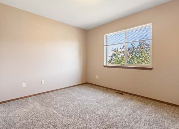 A room with a window showing trees outside.