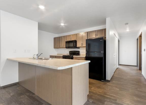 A kitchen with a black refrigerator and wooden cabinets.