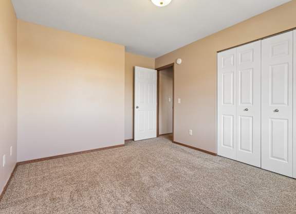 A room with a carpeted floor and white doors.