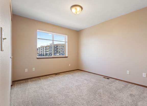 A room with a window showing a view of buildings outside.