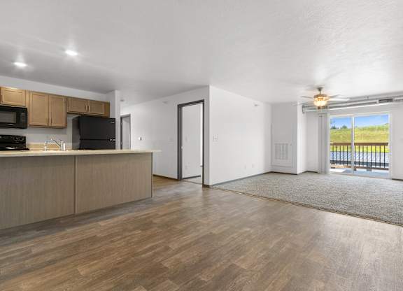 A spacious living room with a kitchen area and a view of the outdoors.