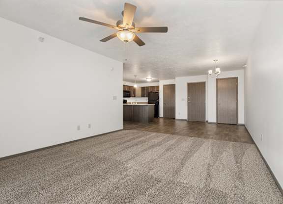 A room with a ceiling fan and carpeted floor.
