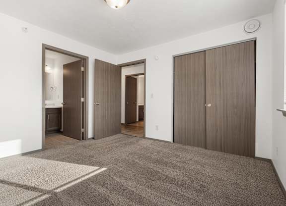 A room with a carpeted floor and three doors.