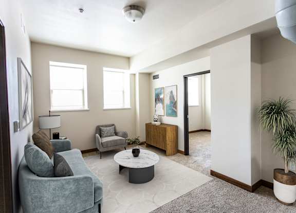 A living room with a grey couch, a white coffee table, and a plant.