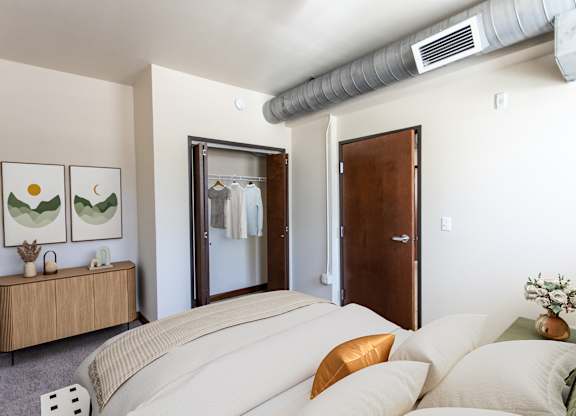A bedroom with a bed, nightstand, and a painting on the wall.