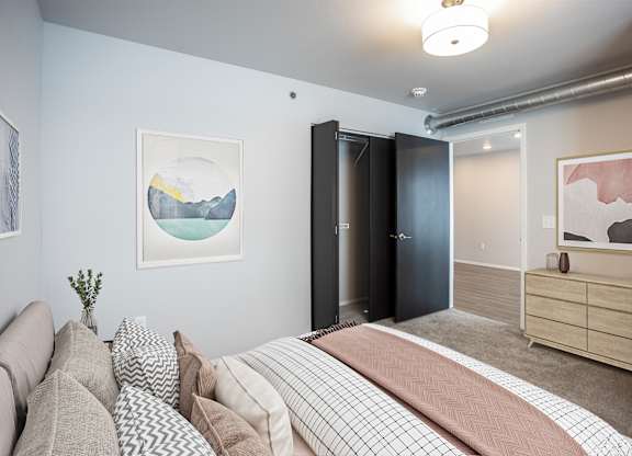 A bedroom with a bed, couch, and artwork on the walls.