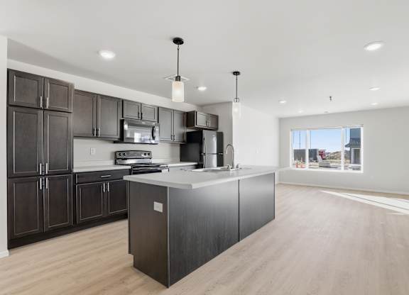 A modern kitchen with dark wood cabinets and a large island.
