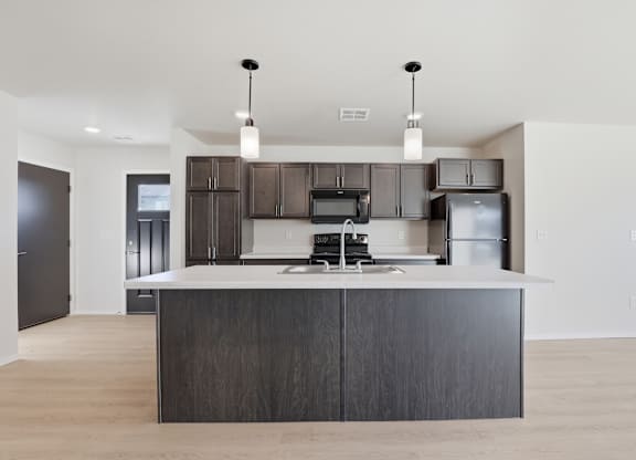 A modern kitchen with a dark wood island and stainless steel appliances.
