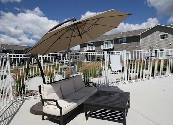 A patio with a couch and umbrella.