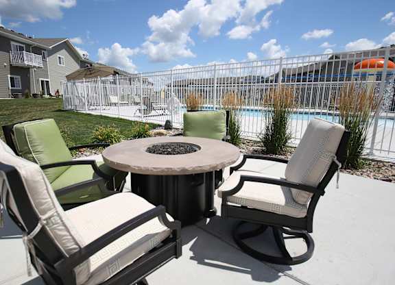 A patio with a table and chairs overlooking a pool.