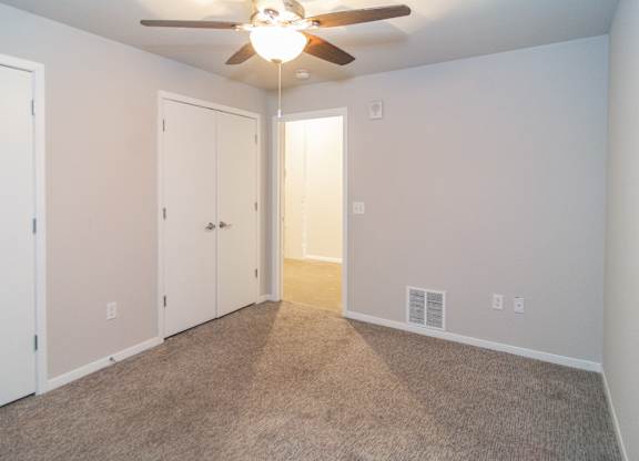 A room with a ceiling fan and carpeted floor.