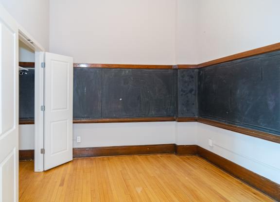 A room with a blackboard on the wall and a wooden floor.