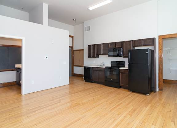 A kitchen with black appliances and wooden floors.