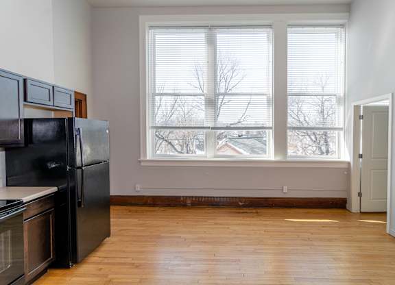 A kitchen with black appliances and wooden floors.