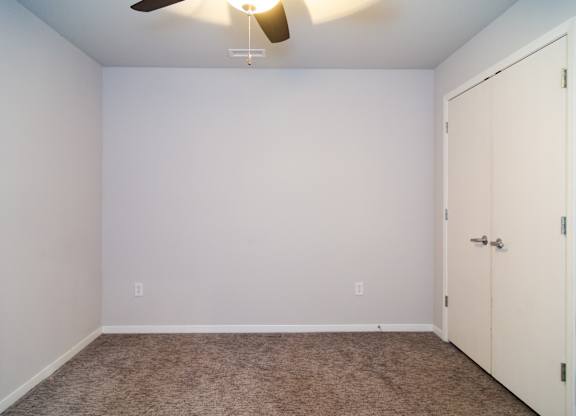 A room with a ceiling fan and a closed door.