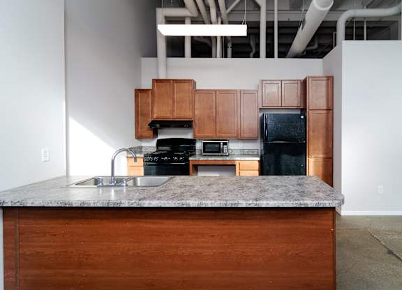 A kitchen with a granite countertop and wooden cabinets.