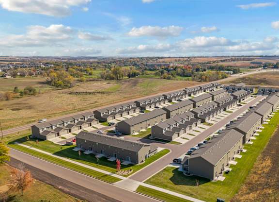 A large housing complex with multiple buildings and a green lawn in the foreground.