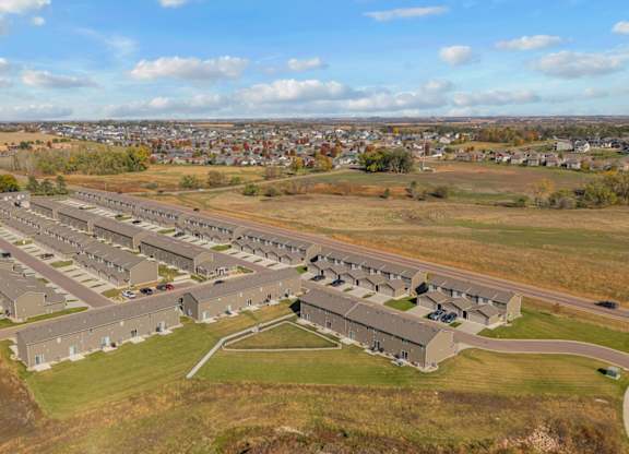 A large, modern building complex sits in a grassy field with a small town in the background.
