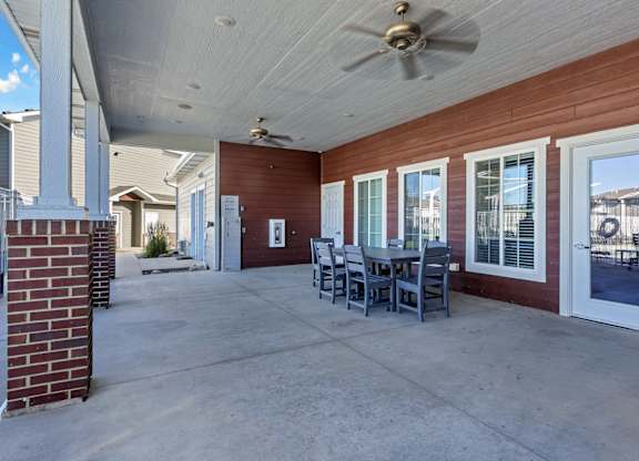 A patio with a table and chairs is covered by a roof.
