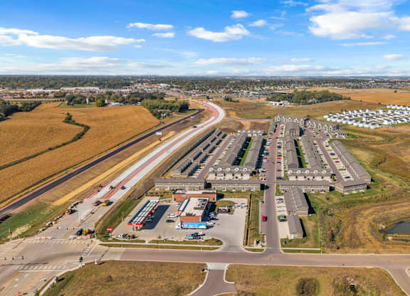 An aerial view of a large parking lot with a building and a road.
