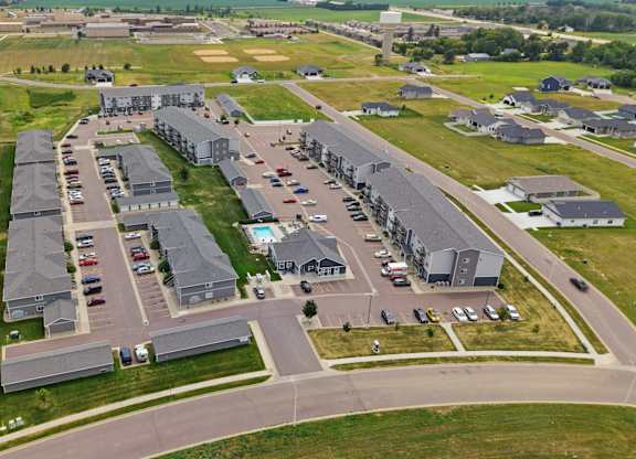 A large, modern building complex with a parking lot in front.