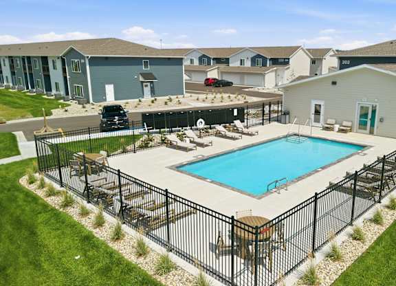 A black fence surrounds a blue swimming pool.