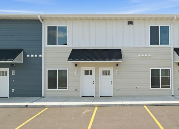 A building with grey and white exterior and black awnings.