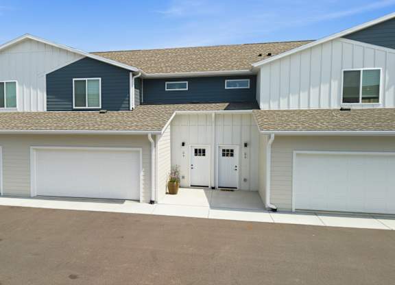 A row of garages with white doors and brown roofs.
