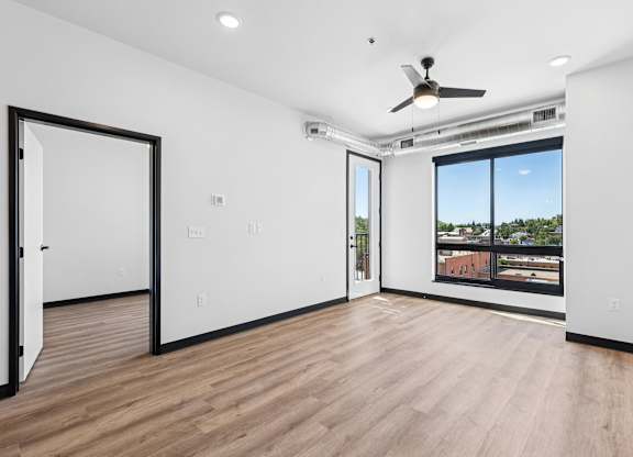 A room with a ceiling fan and a window overlooking a cityscape.