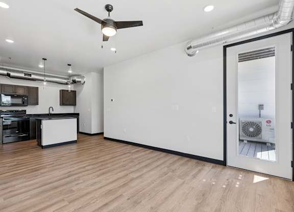 A room with a ceiling fan and a kitchen area.